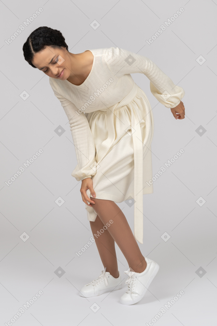 Young woman bowing down in pain and holding her knee