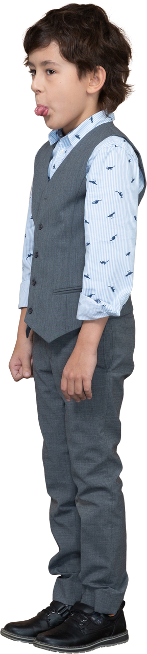 Vista laterale di un ragazzo carino in abito grigio che mostra la lingua