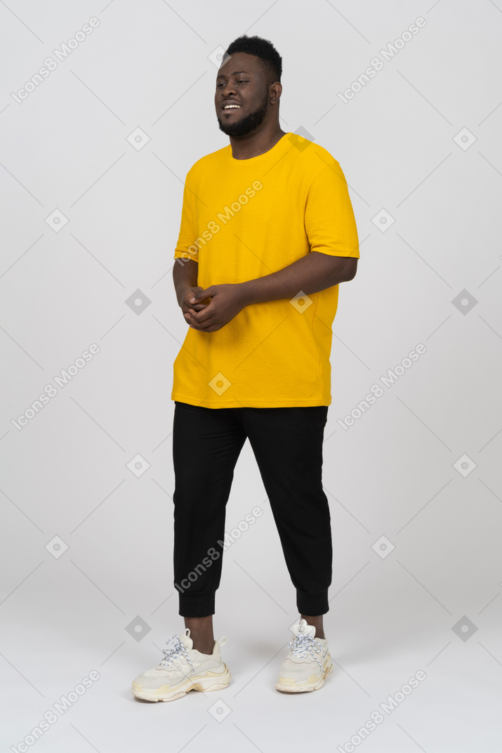 Vista di tre quarti di un giovane uomo dalla pelle scura in maglietta gialla che si tiene per mano insieme