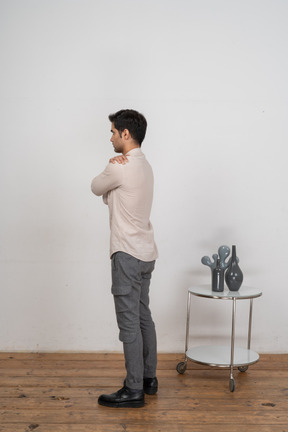 Side view of a man in casual clothes hugging himself