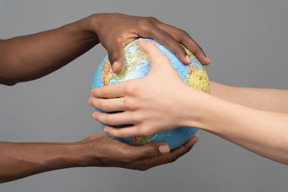 Different hands holding the earth globe