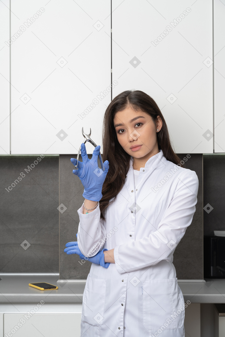 Front view of a female doctor holding her dental instrument and looking at camera