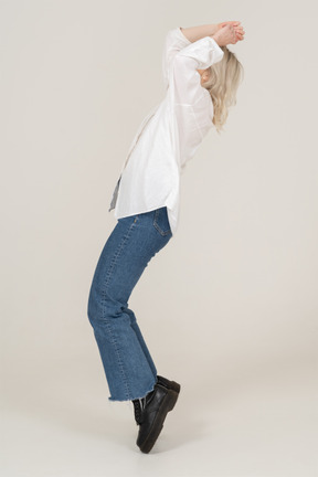 Side view of a blonde female raising hands and standing on her tiptoes