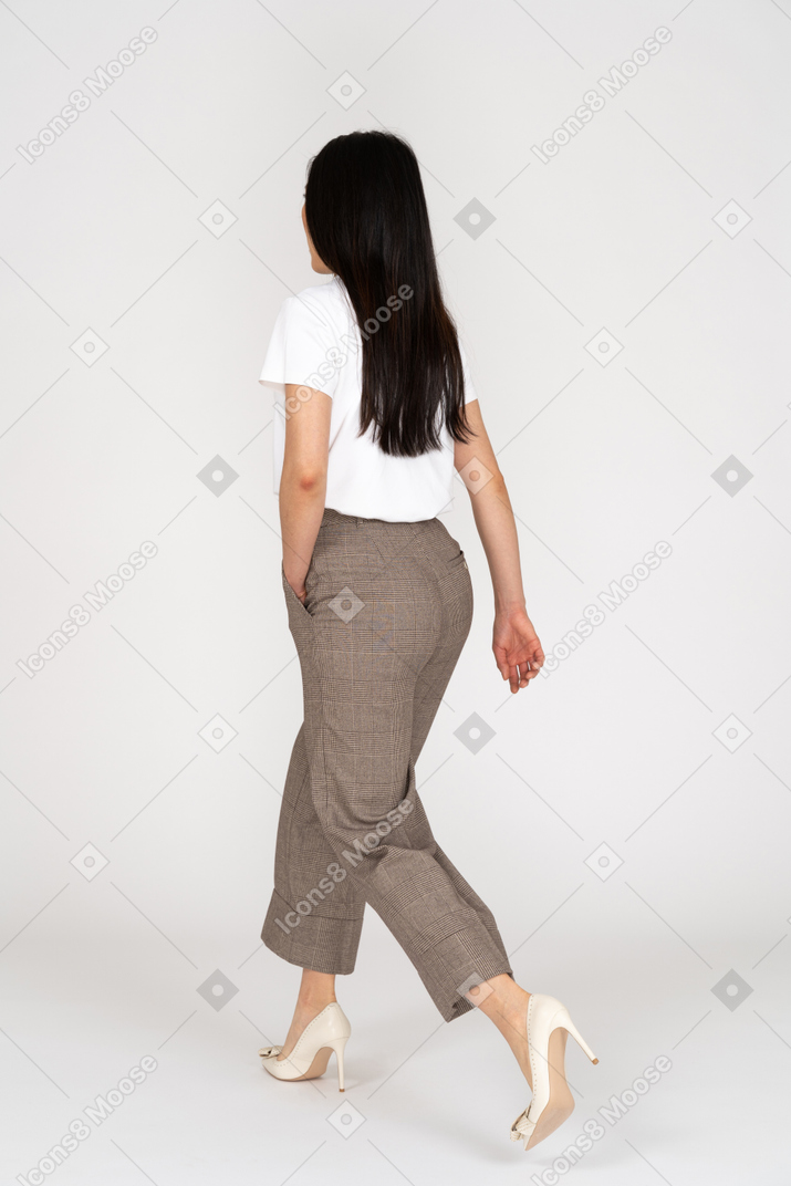 Three-quarter back view of a walking young lady in breeches and t-shirt