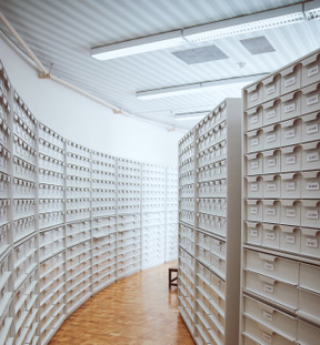 An empty room with long rows of shelves containing lots of boxes with labels