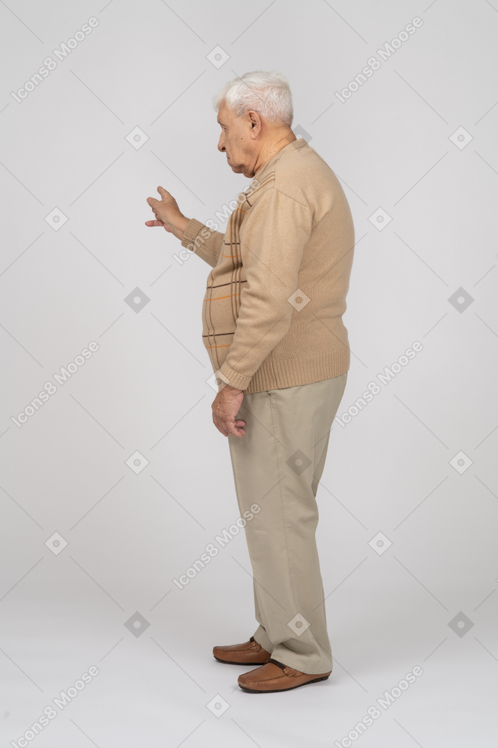 Vista lateral de um velho em roupas casuais, apontando com o dedo