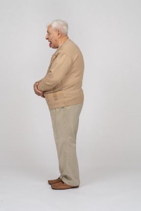 Vista lateral de um velho em roupas casuais, mostrando a língua
