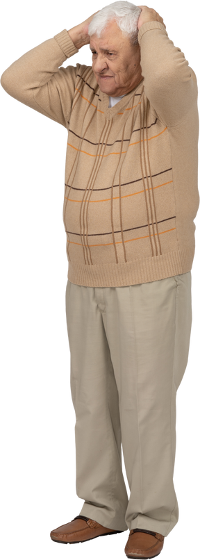 Вид спереди испуганного старика в повседневной одежде, стоящего с руками на голове