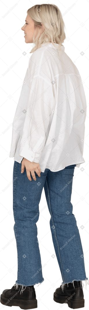 Vue latérale d'une femme blonde dans des vêtements décontractés debout et à côté