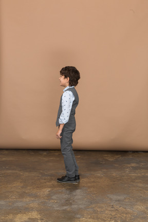 Boy in grey suit standing in profile