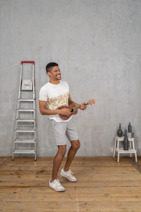 Three-quarter view of a man playing ukulele and enjoying himself