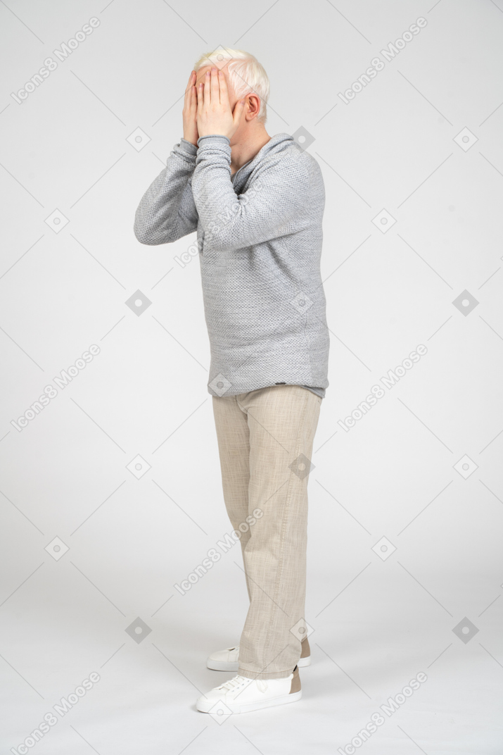 Standing man covering his face with his hands