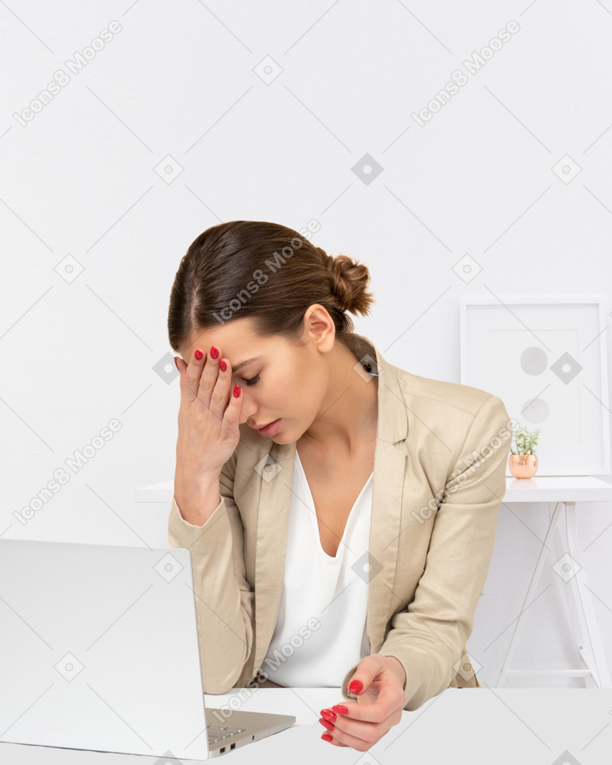 Tired young woman sitting in front of her laptop