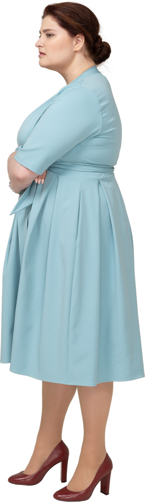 腕を組んでポーズをとる青いドレスの女性