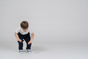 Little boy in casual clothes bending forward