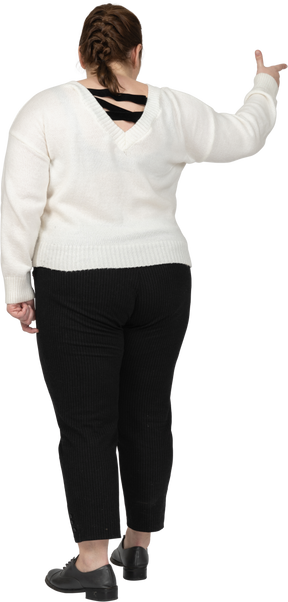 Rear view of a plump woman in casual clothes pointing with a finger
