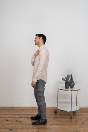 Side view of a man in casual clothes posing with hand on chest