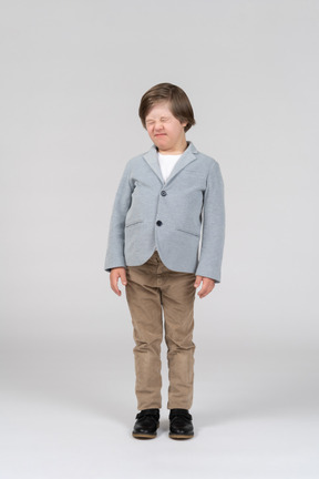 Boy wearing gray jacket and khaki pants scrunching up his face