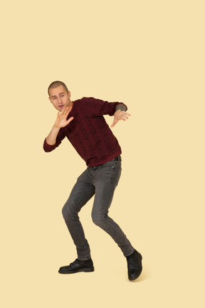 Three-quarter view of a protecting young man dressed in red pullover