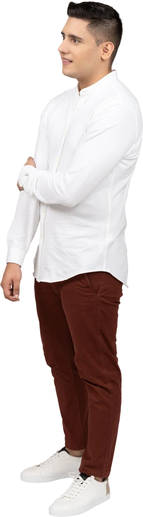 Three-quarter view of a young latino man holding his elbow and smiling uncertainly