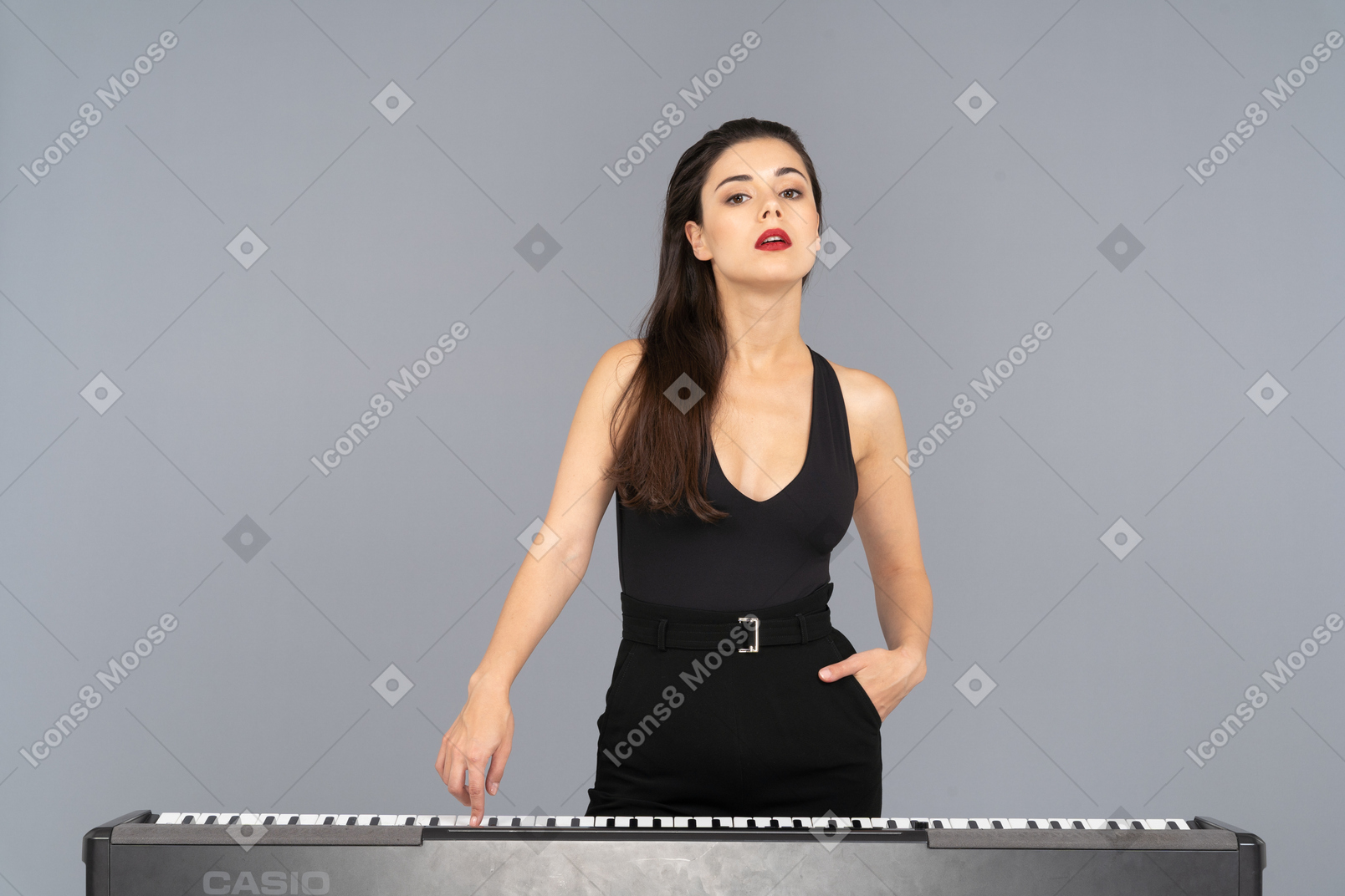 一位年轻的女士，穿着黑色连衣裙，按下钢琴的键的前视图