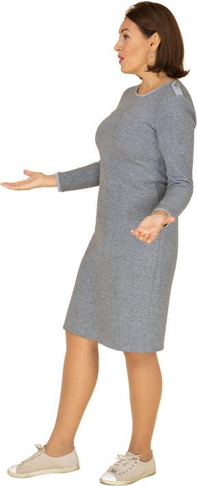 Vue latérale d'une femme triste en robe grise faisant des gestes