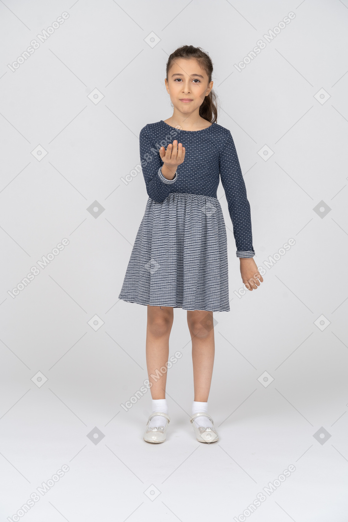 Vista frontal de una niña de pie con una palma levantada