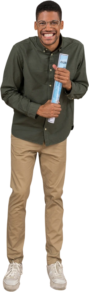Front view of a man smiling shyly and holding on to a rolled-up map