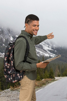 A man standing on the side of a road pointing at something