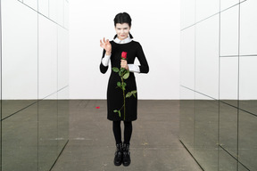 A woman in a black dress holding a rose