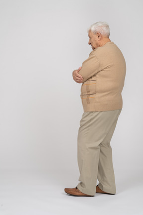 一位身穿休闲服、双臂交叉站立的老人的侧视图