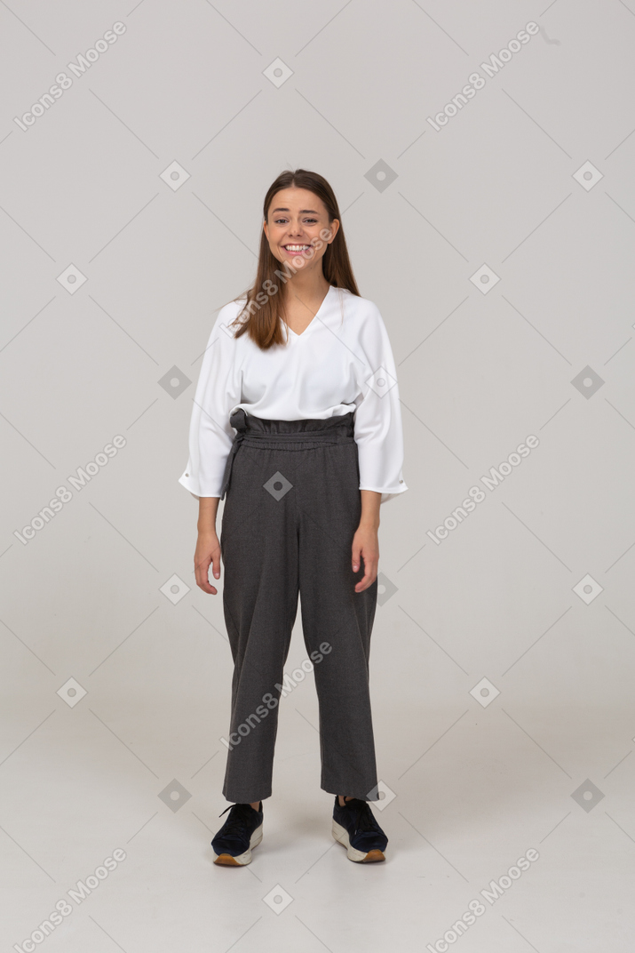Vue de face d'une jeune femme souriante en vêtements de bureau regardant la caméra
