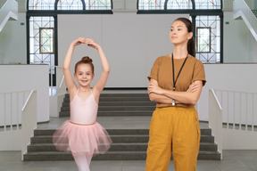 Professora de dança olhando orgulhosamente para seu pequeno aprendiz