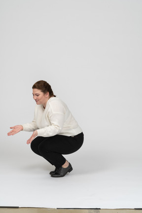 Side view of a plump woman in casual clothes squatting