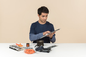 A young man in casual blue clothes working with computer details