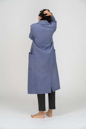 Back view of a woman in coat pulling her hair