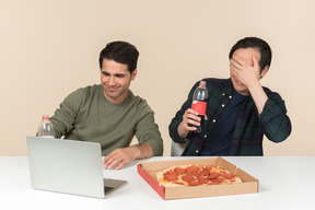 Interracial friends watching movie on laptop and one of them seems afraid