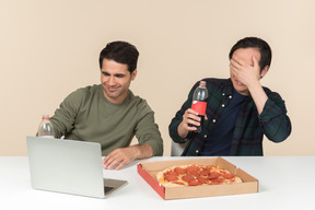 Amigos interraciales viendo películas en la computadora portátil y uno de ellos parece asustado