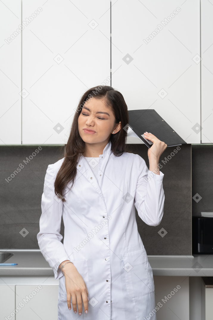 Vista frontal de uma mulher perplexa fazendo uma careta e segurando um tablet