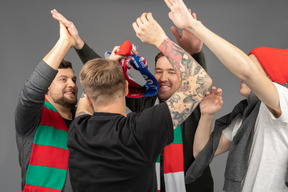 Close-up of four happy male football fans giving high five