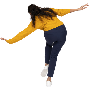 Rear view of a girl in casual clothes posing on one leg with outstretched arms
