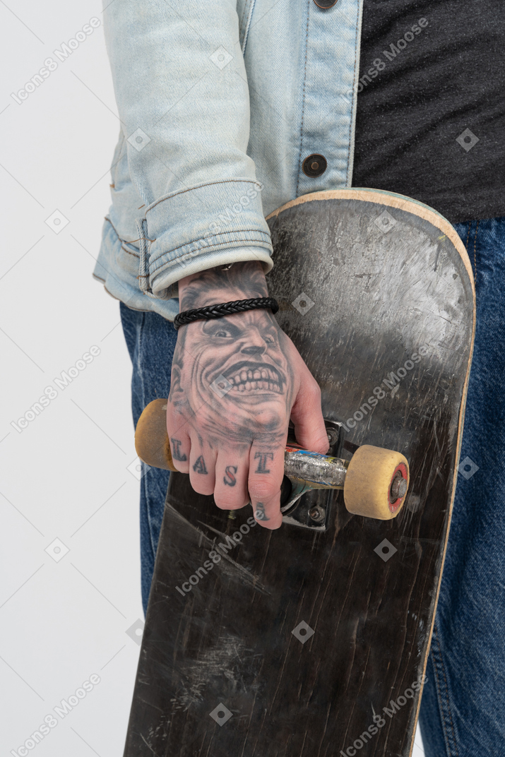 Skateboard in tattooed hands