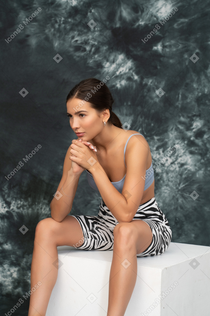 Close-up a concentrated woman in sports suit sitting on a cube