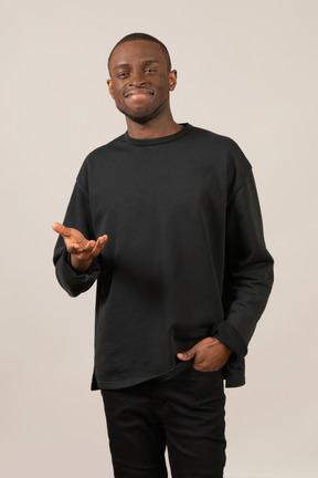 Front view of a young man smiling and holding hand up