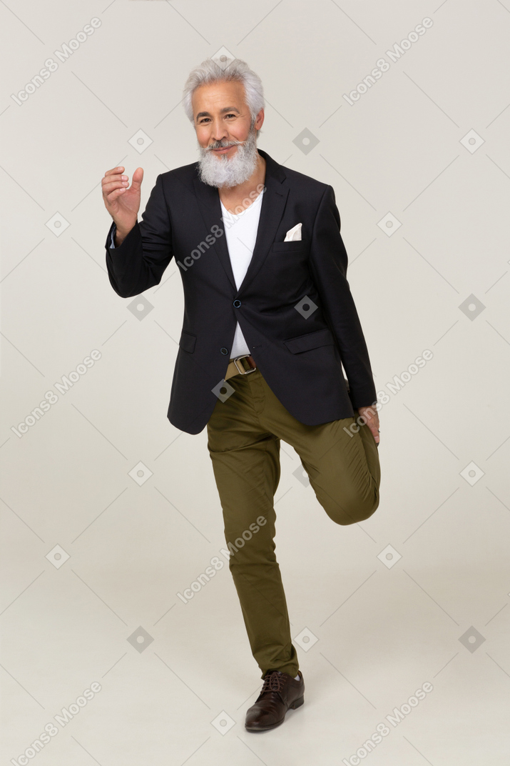 Hombre alegre en una chaqueta de pie sobre una pierna