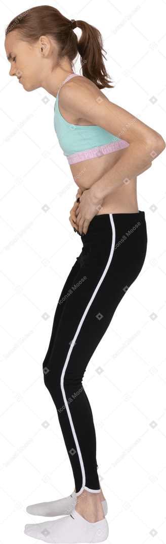 Vista laterale di una ragazza adolescente in abiti sportivi toccando lo stomaco e chinandosi