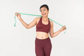 Young indian woman in sporstwear standing with cloth ruler on her neck