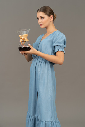 Three-quarter view of a young woman in blue dress holding a pitcher of wine