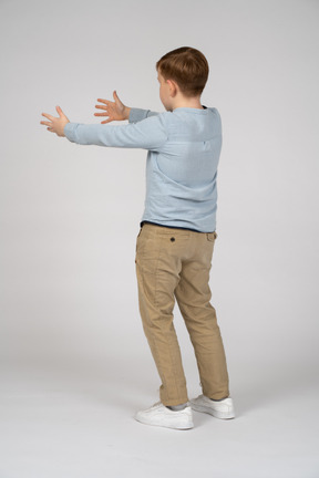 Back view of little boy outstretching his arms