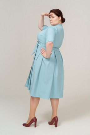 Rear view of a woman in blue dress looking for someone